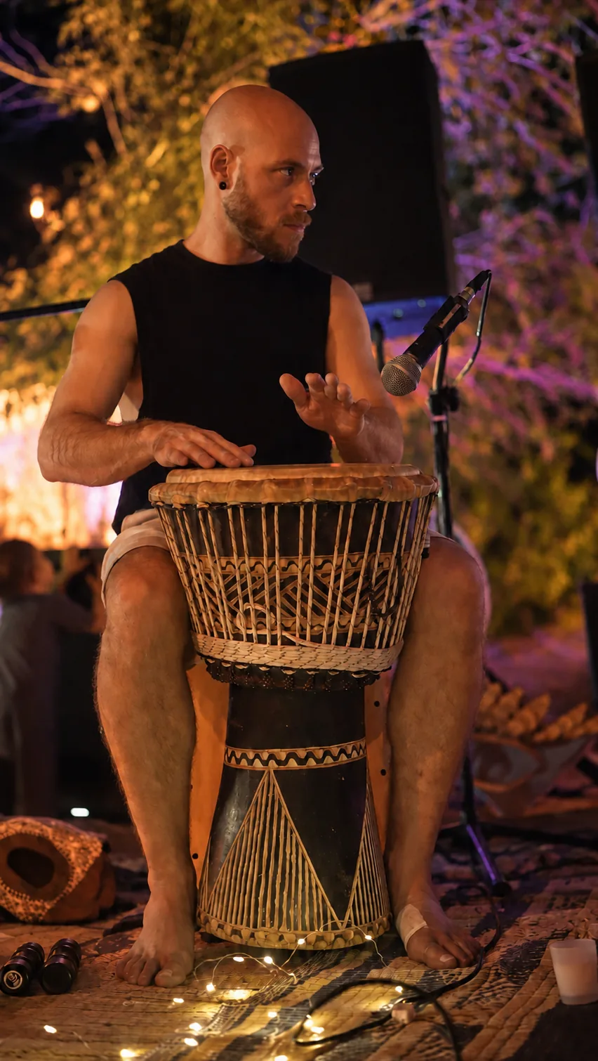 מתופף מנגן על ג'מבה על הבמה בלילה